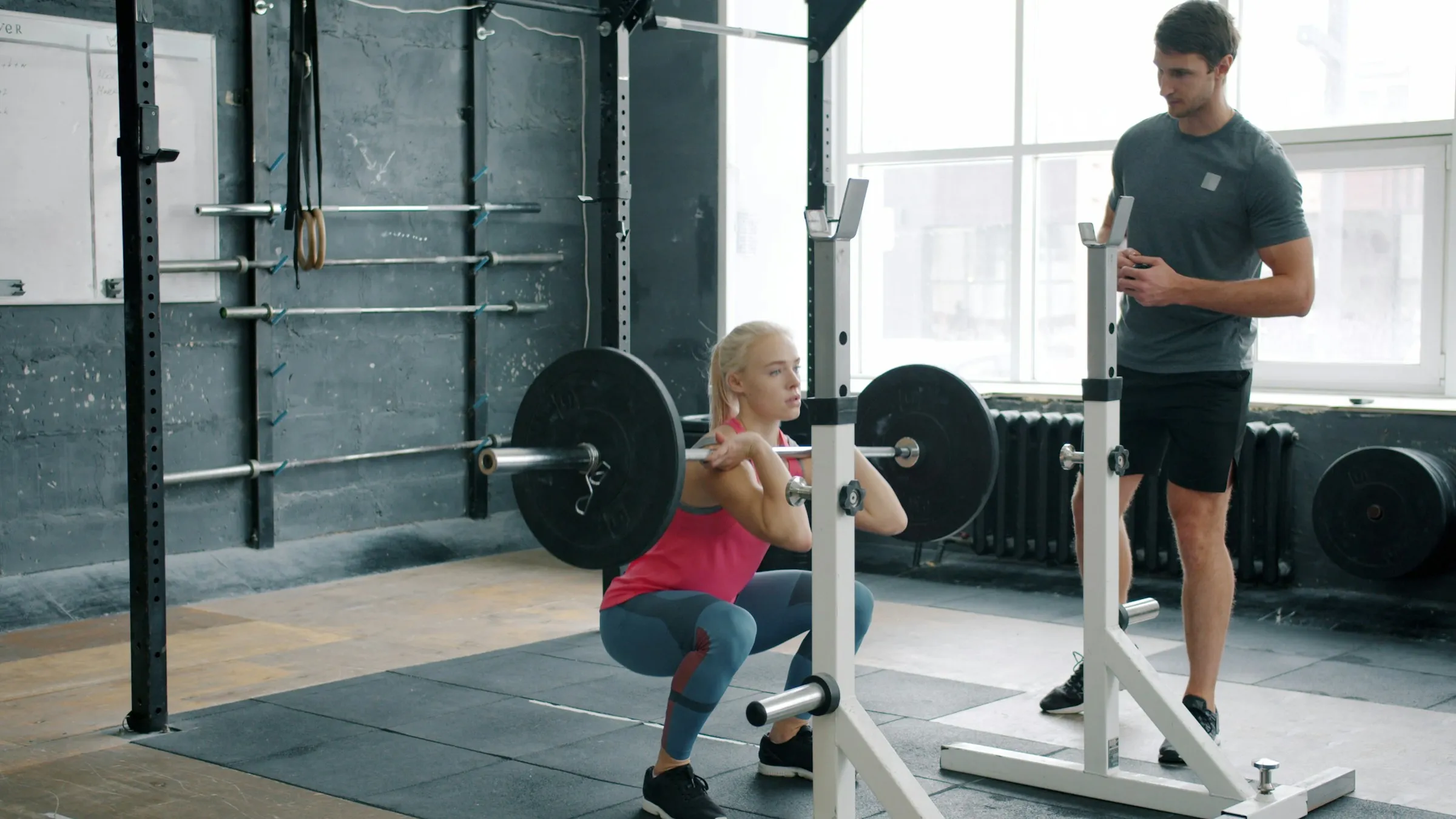 A coach watching an athlete squat