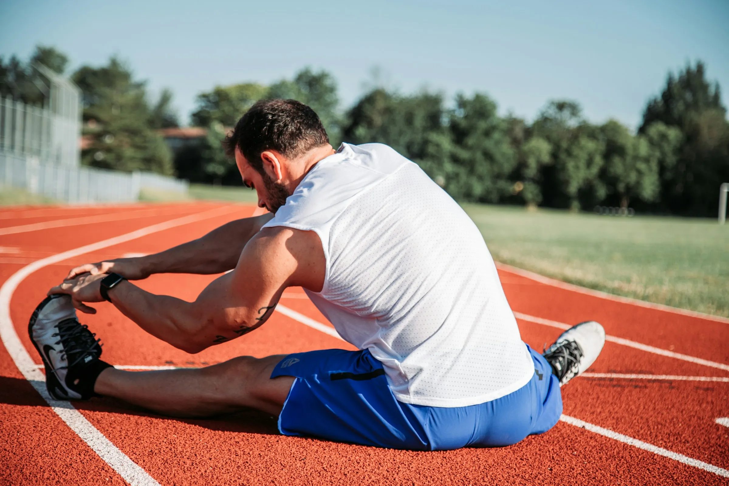 An athlete stretching his hamstring on the track
